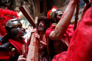 Ator vestido como Jesus Cristo carrega uma cruz em caminhada pela Via Dolorosa, na direção à Igreja do Santo Sepulcro, na Cidade Velha de Jerusalém — Foto: Ariel Schalit/AP 